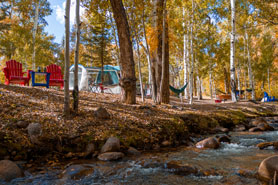 Creekside tent sites with chairs and firepit at Creekside Chalets and Cabins: Year-Round Quality Vacation Rentals in Salida, Colorado.