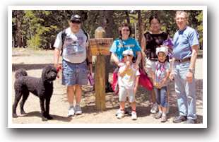 Family in front of hiking trail sign on Mount Blue Sky Scenic Byway, Colorado.